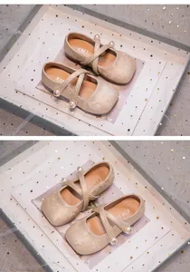 Detail view of champagne Hanfu shoes with floral patterns and pearl accents in a box.