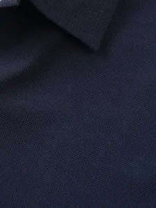 Vue rapprochée de la texture gaufrée bleu marine d'un polo pour homme à manches courtes