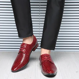 Detail view of red glossy crocodile embossed pointed leather shoes for men on a model.