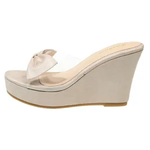 Eleganti sandali con zeppa beige con un fiocco di tendenza e cinturino trasparente.