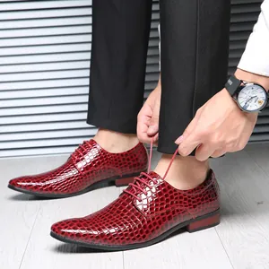 Detailed view of red glossy pointed-toe dress shoes with crocodile texture for men