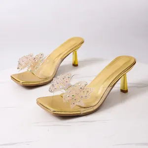 Dettaglio delle eleganti scarpe dorate a punta quadrata con fiocco a farfalla decorato con strass