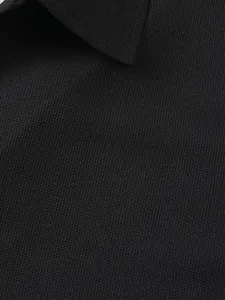 Vue macro détaillée montrant la texture du tissu en maille gaufrée noire d'un polo pour hommes