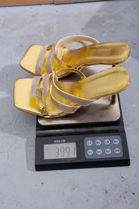 Detaillierte Nahaufnahme von eleganten goldenen Sandaletten, die auf der Waage 399,1 g wiegen
