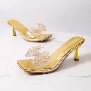 Dettaglio di eleganti sandali dorati con tacco alto e un fiocco di strass luccicanti