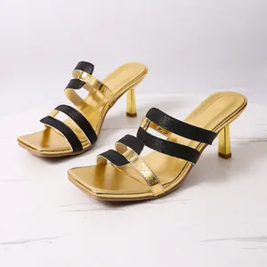 Detailansicht eleganter schwarz-goldener Stöckelsandaletten mit modischer eckiger Zehenpartie.