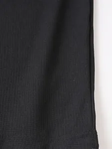 Gros plan sur la texture respirante en maille gaufrée noire d'un polo pour hommes.