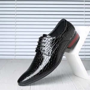 Detail view of men's glossy black pointed dress shoes with embossed stone texture.