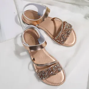 Detail view of champagne gold flat sandals with sparkling sequin straps