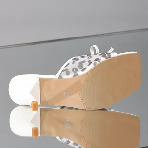 Detailed macro shot of the durable sole and leopard mesh on white high-heel mules.