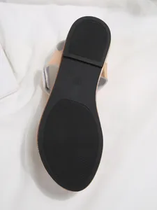 Detailed view of the black textured anti-slip sole of a metallic rose gold flat sandal