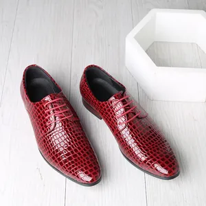 Glossy red men's pointed-toe oxfords with embossed stone texture on a wooden background.