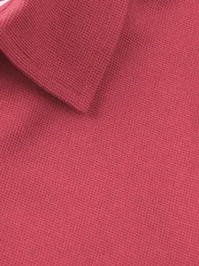 Détail de la texture en maille gaufrée rose et du col d'un polo de sport pour hommes.