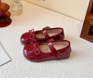 Detail view of wine red patent leather girls' Mary Jane shoes with bow tie and strap