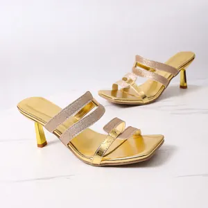 Elegante goldene Sandaletten mit Glitzer- und Metallic-Riemen auf Marmorhintergrund