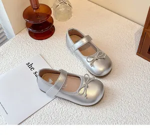 Elegant silver girl's princess Mary Jane shoes with bow detail on white textured surface