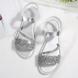 Detailed view of silver glittery straps and Velcro closure on flat sandals