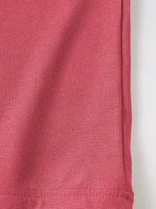 Détail de la texture en maille gaufrée rose et des coutures de l'ourlet d'un polo pour homme