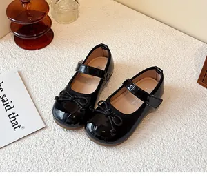 Close-up view of elegant black patent leather Mary Jane shoes for girls with bow detail.
