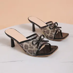 Detailed side view of leopard print mesh high heel mules with black bow and square toe