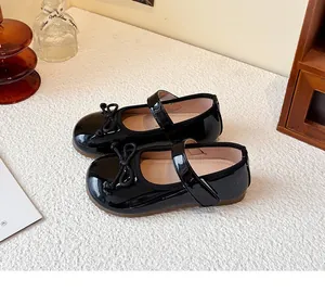 Detailed close-up view of black patent leather girls Mary Jane shoes with bow decoration