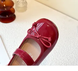 Close-up detail of glossy red patent leather girls' Mary Jane flats with bow decoration