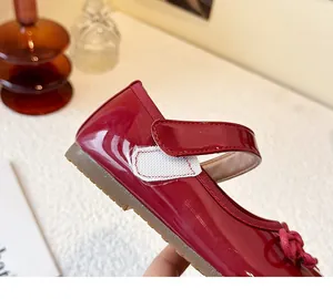 Detailed view of red patent leather girl's Mary Jane shoes with soft gum sole and bow.
