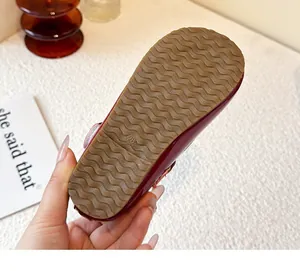 Detail view of the durable anti-slip wavy rubber sole on a girl's burgundy shoe