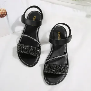 Macro view of black women's flat sandals featuring sparkly rhinestone bands and straps