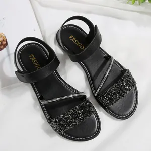 Detail view of stylish black flat sandals with sparkling glitter and rhinestone straps