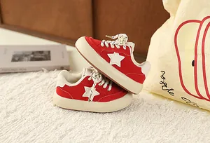 Close-up detail of children's retro red sneakers featuring a white star patch and thick cream soles