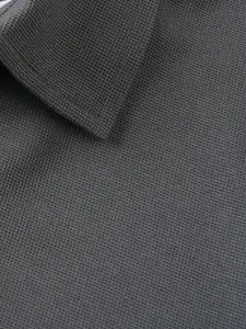 Détail en gros plan du tissu en maille gaufrée gris foncé et du col d'un polo pour homme