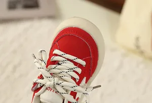 Close-up detail of children's red retro sneaker featuring star design and patterned laces