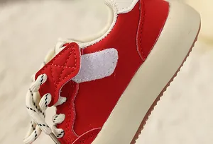 Close-up of red and beige children's retro sneaker with velcro strap and thick sole.