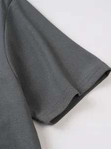 Détail macro du tissu en maille gaufrée respirante sur la manche d'un polo gris pour homme