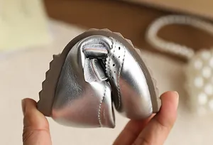 Close-up of flexible silver soft-sole girl's princess shoe showing bending ability