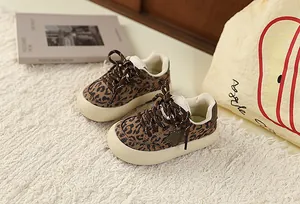 Leopard print toddler sneakers with star detail and thick soles on a textured rug.