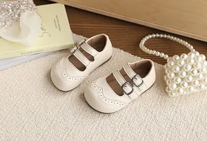 Close-up view of cream-colored British style children's leather shoes with buckles.