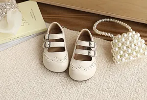 Close-up of the brogue detailing and double buckle straps on cream children's shoes