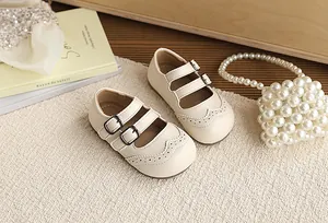 Close-up of cream British style toddler Mary Janes with brogue detailing and buckles