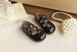 Elegant black children's Mary Jane shoes with double straps on textured background