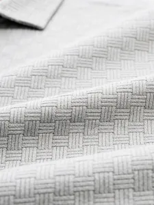 Macro view of the intricate woven jacquard fabric texture on a grey casual polo shirt