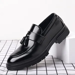 Vue détaillée des mocassins élégants à pampilles en cuir noir pour hommes sur bloc blanc.