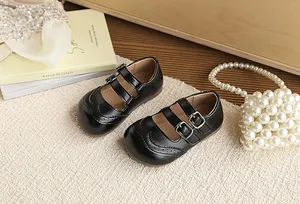 Close-up of children's black British-style leather Mary Janes with double buckle straps.