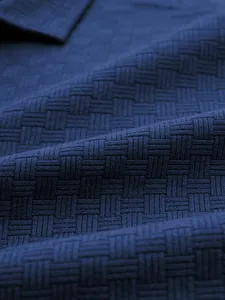 Close-up macro view of navy blue basket-weave jacquard texture on men's polo shirt