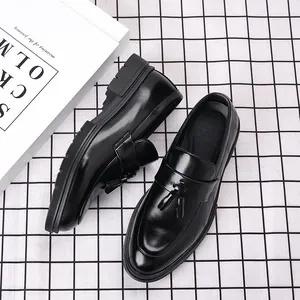 Gros plan de mocassins à glands en cuir noir brillant pour hommes sur fond à carreaux noirs