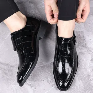 Detailweergave van zwarte herenloafers met krokodillenreliëf en metalen gesp