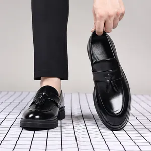 Détail de mocassins en cuir noir à glands, finition brillante et semelle épaisse