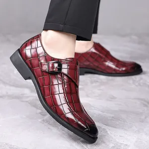 Close-up van bordeauxrode loafers met krokodillenprint en stijlvolle metalen gesp aan voet