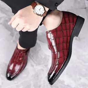 Detailopname van bordeauxrode herenloafers met krokodillenpatroon, zwarte zool op marmeren vloer.